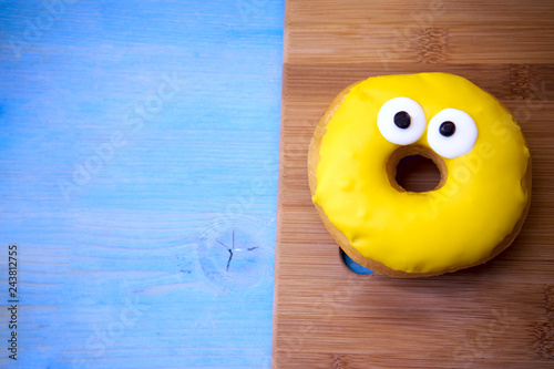 Yellow tasty donut lies on a wooden plank