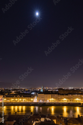 Grenoble, France, January 2019 : City at night with isere river, the moon and stars in the sky © florent