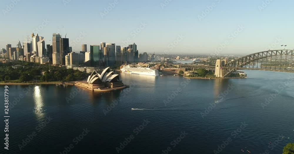 Circular Quay Sydney city CBD waterfront on shores of Harbour with the Bridge in aerial backwards aerial flying over water surface and kayaks.
Circular Quay Sydney city CBD waterfront on shores of Harbour with the Bridge in aerial backwards aerial flying over water surface and kayaks.