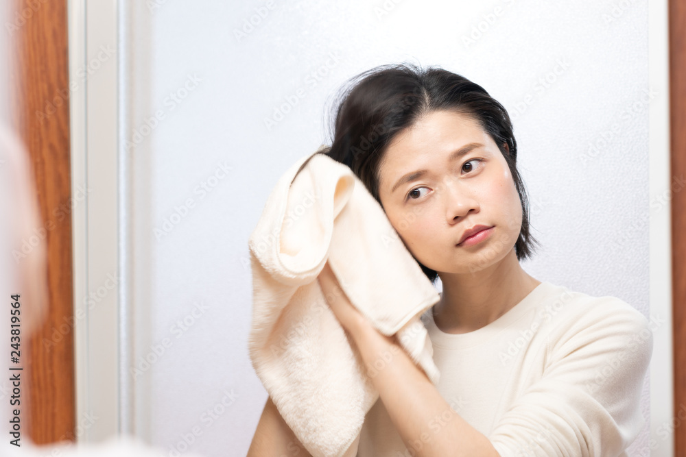 asian female wiping hair with towel in bathroom asian female wiping hair with towel in bathroom