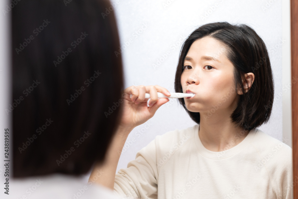 asian female brushing her teeth in bathroom asian female brushing her teeth in bathroom
