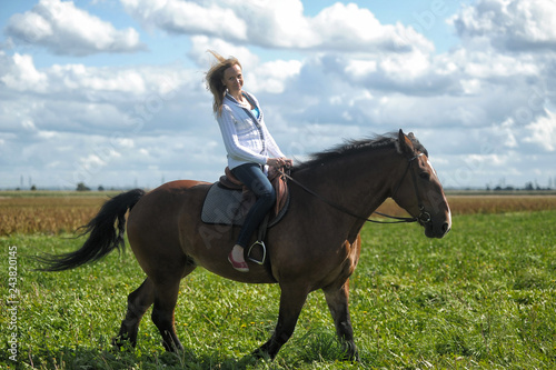 blonde riding a horse in a field