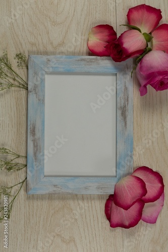 Empty photo frame with rose flower and petals