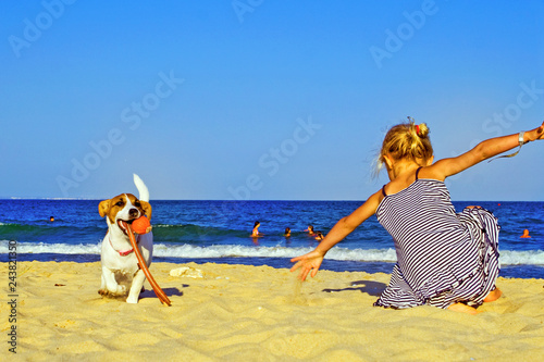 little girl playing with puppy jack russel terrier on the beach near the sea