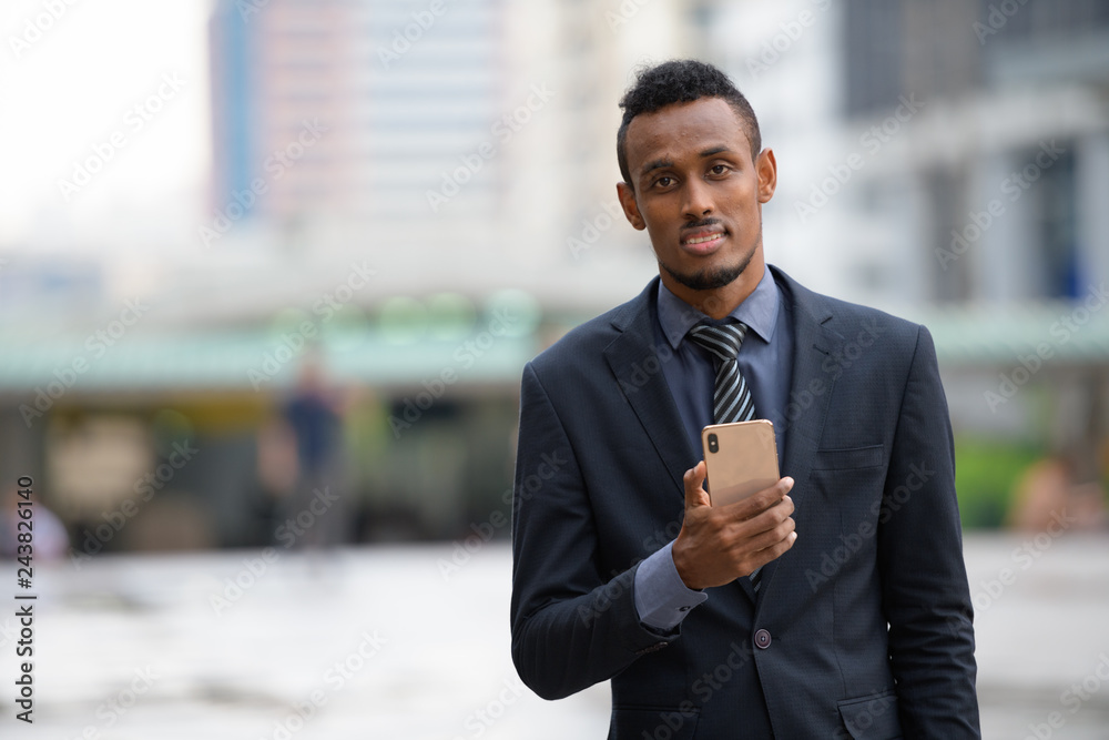 Happy young African businessman using phone in the city Happy young African businessman using phone in the city