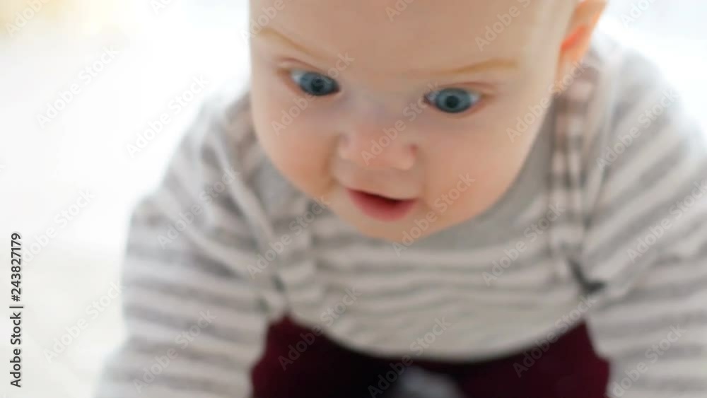 The baby girl learns to crawl, the first attempts to crawl. Baby crawls to the camera, smiling and laughing on the floor in the white room The baby girl learns to crawl, the first attempts to crawl. Baby crawls to the camera, smiling and laughing on the floor in the white room