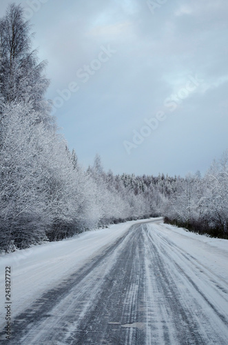 Snowy road through the forest in winter
