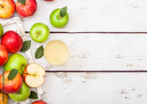 Glass of fresh organic apple juice with red and green apples in vintage box on wooden background