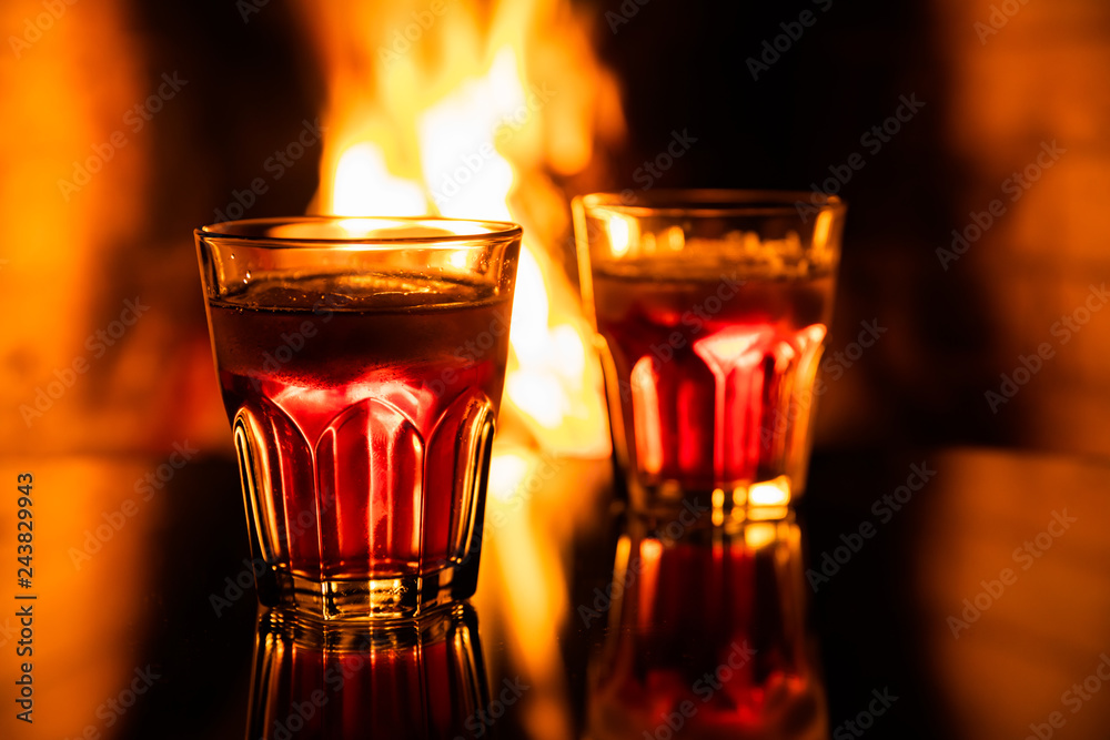 Glass of whiskey with ice near the fireplace Glass of whiskey with ice near the fireplace