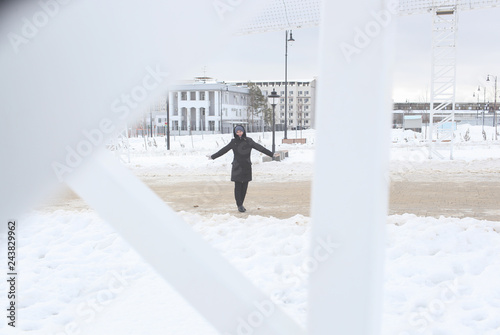 Portrait of the freezing woman in the winter through a white frame of city designs. A portrait on a belt