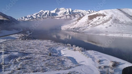 Flying towards snow covered mountain over lake with low foggy clouds in winter landscape in Utah viewing Timpanogos. photo