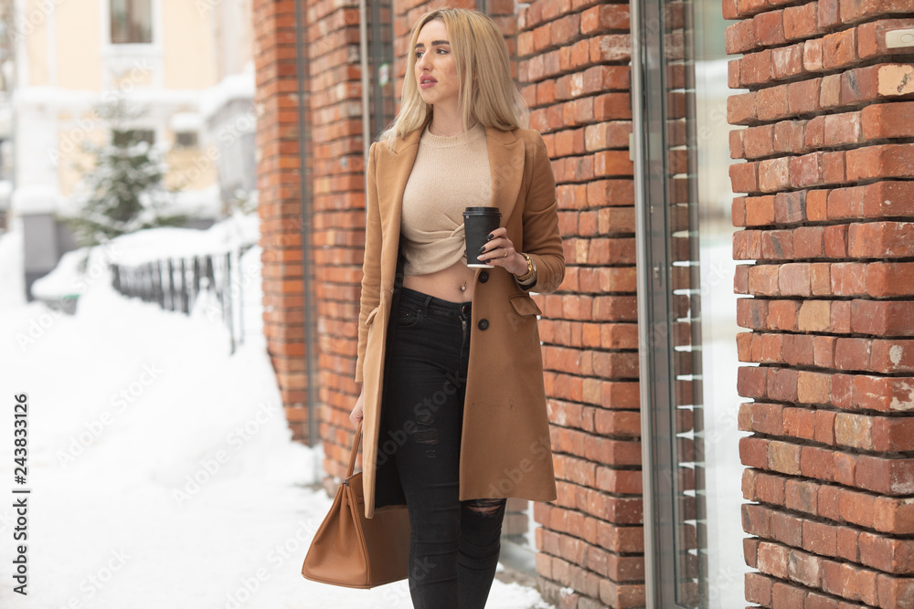lifestyle and people concept: Smiling stylish young woman drinking coffee while walking on a city street lifestyle and people concept: Smiling stylish young woman drinking coffee while walking on a city street