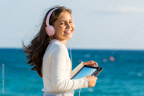 Bilde på lerret Cute tween girl with headphones and tablet outdoors.