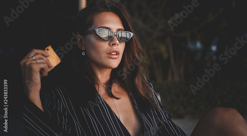 Obraz na płótnie Outdoor fashion photo of young beautiful lady in sunglasses at villa. sexy woman holding piece of pineapple. Summer vibes w salonie