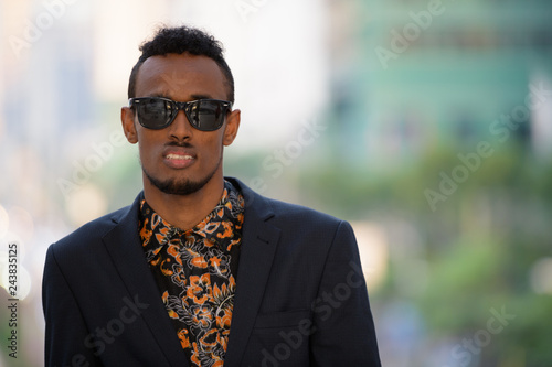 Face of young African businessman wearing sunglasses outdoors photo