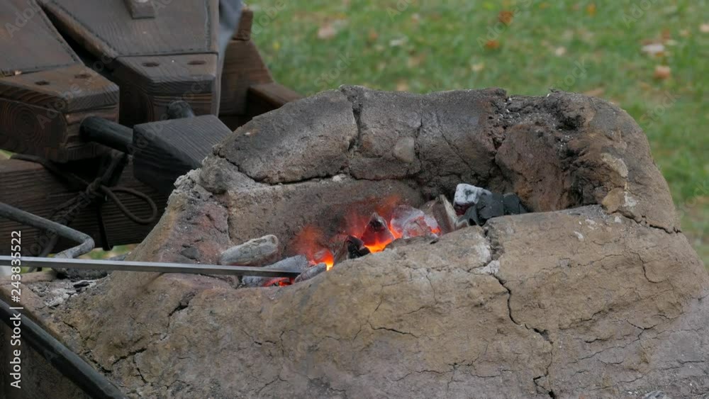 Medieval furnace with burning coals and fire lit with bellows in blacksmith forge Medieval furnace with burning coals and fire lit with bellows in blacksmith forge