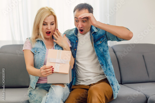 Love, holiday, celebration and family concept - smiling man surprises his girlfriend with present at home