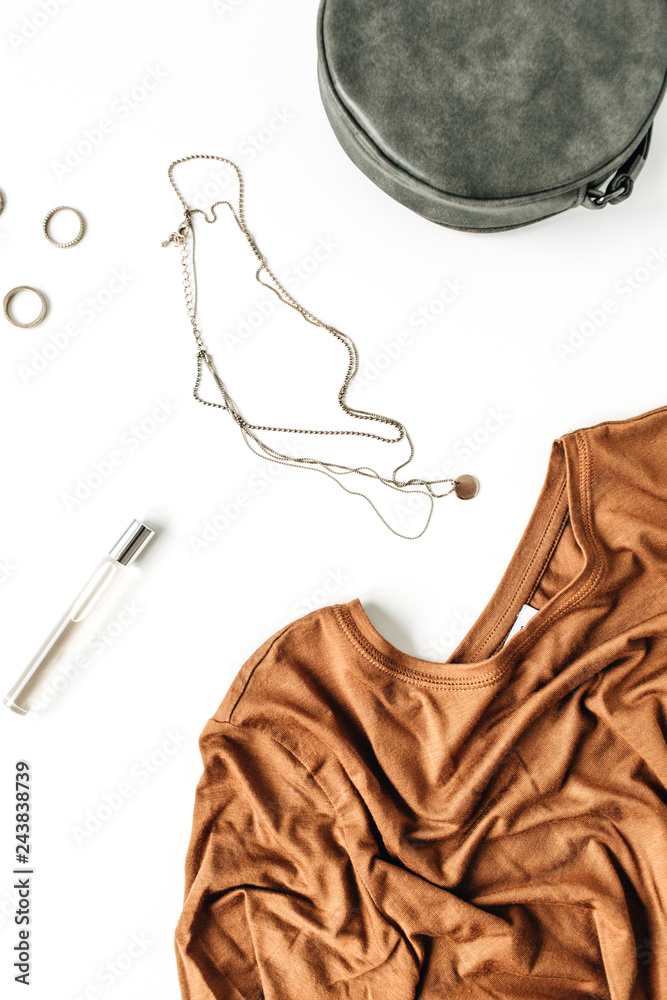 Fashion feminine concept with ginger t-shirt, rings, necklace, purse and lipstick on white background. Flat lay, top view.