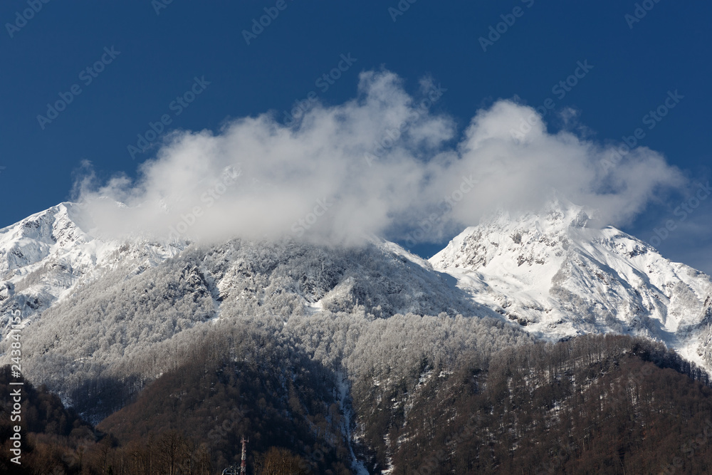 Krasnaya Polyana, Sochi, Russia. The Aibga ridge in the snow. Two summit in the clouds