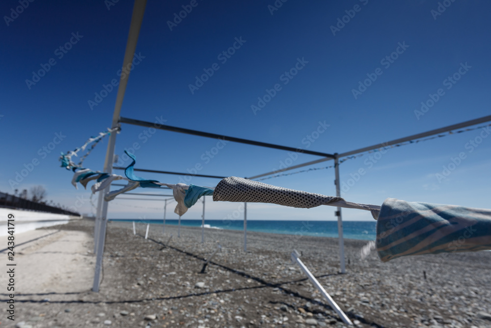 Adler, Sochi, Russia. Flags stretched out on a base wooden canopy, swaying in the wind. Black sea pebble beach