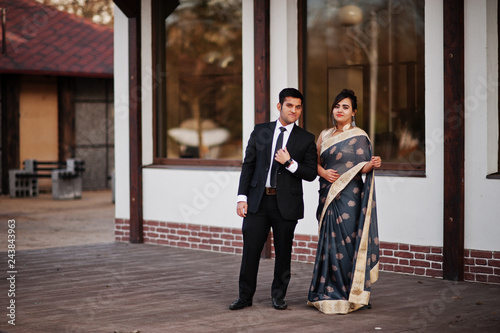Elegant and fashionable indian friends couple of woman in saree and man in suit.