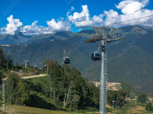 Extreme cable car ride in the mountains. The green slopes of the mountains. Summer rest.