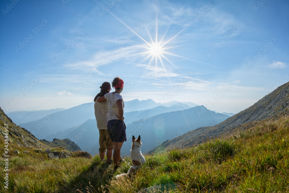 Couple with dog admiring the view from the top of a mountain