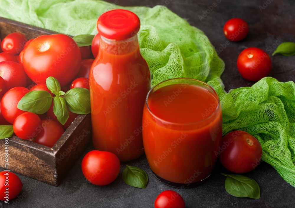 Bottle and glass of fresh organic tomato juice with fresh raw tomatoes in  box on stone kitchen background on black Stock Photo | Adobe Stock