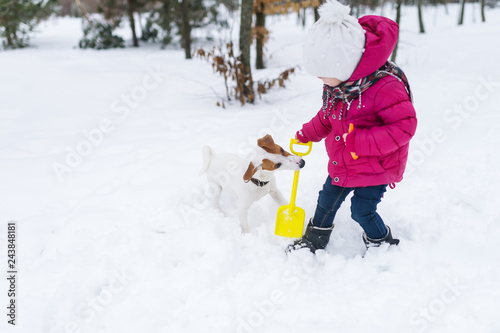 Baby girl with dog play in winter park