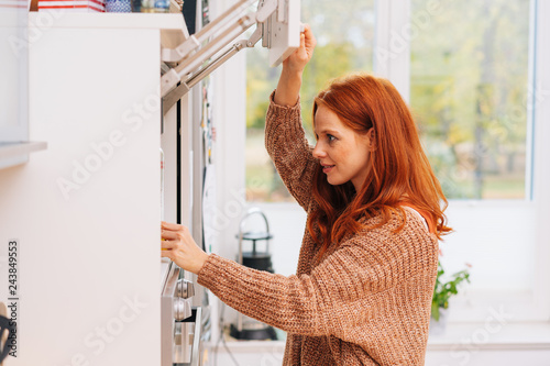Obraz na plátně Woman peeks into kitchen cupboard