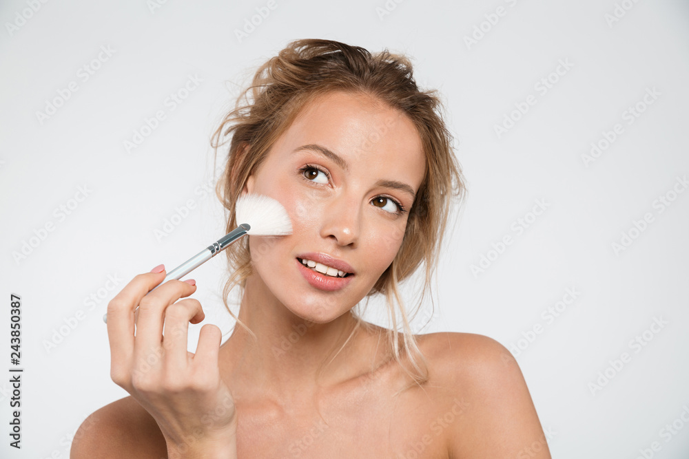 Fototapeta premium Woman posing isolated over white wall background holding makeup brushes.
