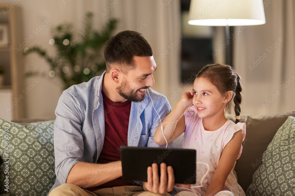 family, fatherhood and technology concept - happy father and little daughter with tablet pc computer and earphones listening to music at home family, fatherhood and technology concept - happy father and little daughter with tablet pc computer and earphones listening to music at home