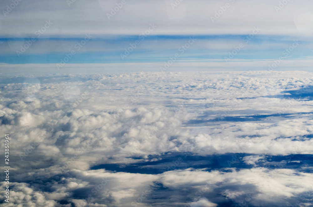 Naklejka premium Airplane illuminator view on fluffy cumulus clouds and blue sky.