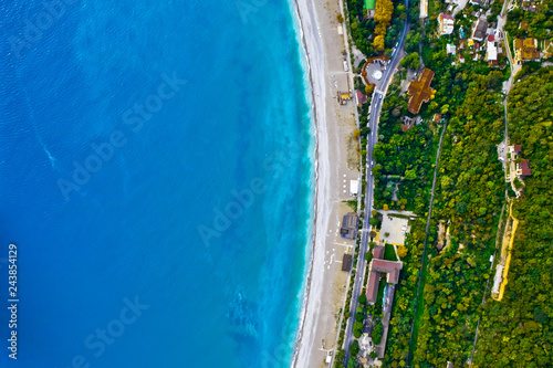 Aerial view from top to bottom of the turquoise sea with green trees