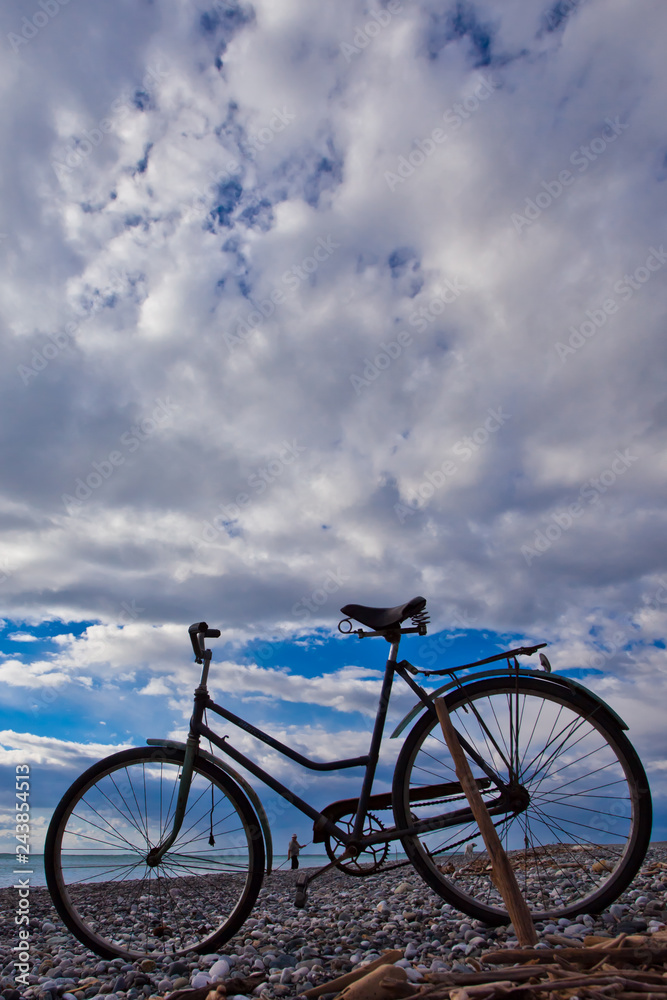 Fototapeta premium Vintage bicycle against the blue sky with clouds and sea.