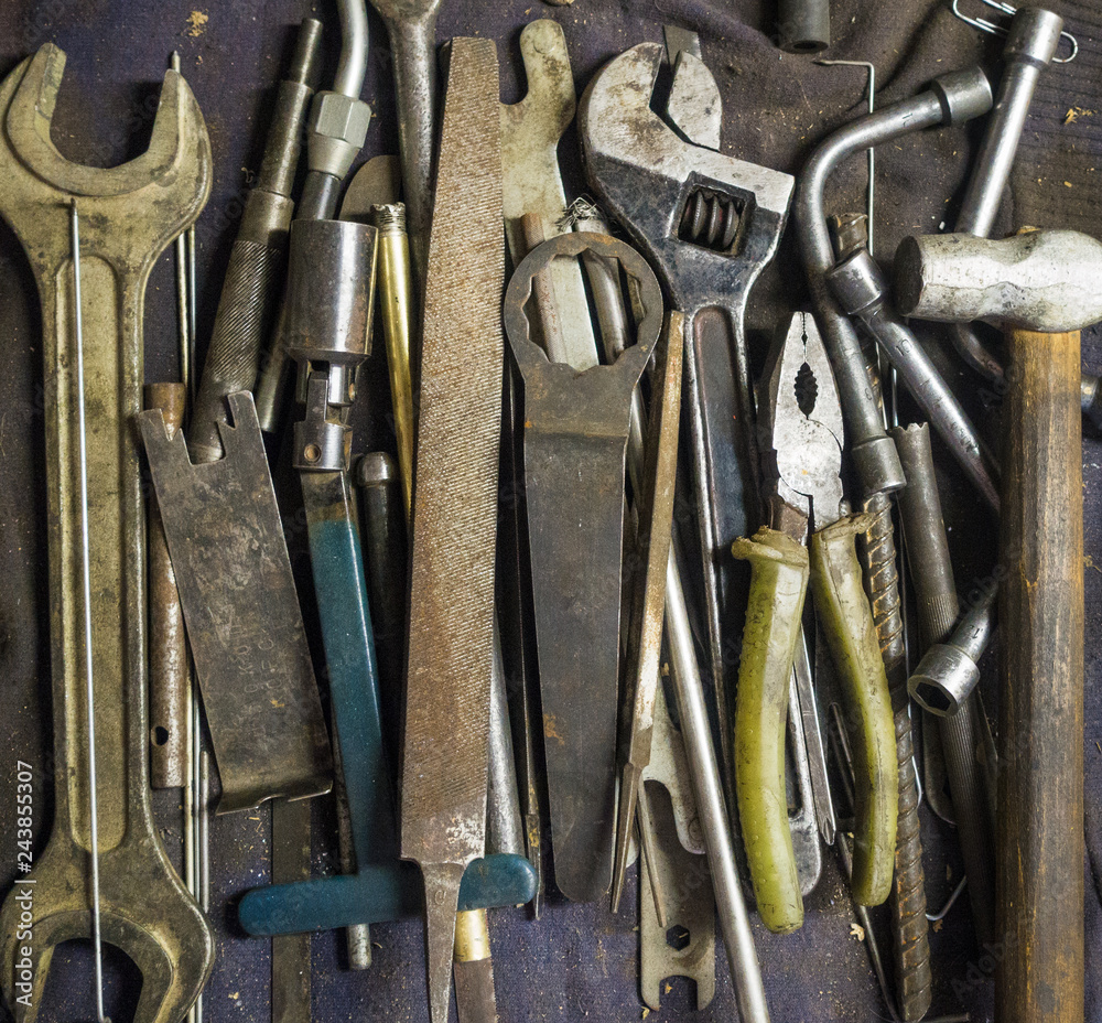 Tools for car and engine maintanance and repair, laying on the garage workbench - pliers, wrenches, files, hammer, adjustable wrench, socket wrenches. Tools for car and engine maintanance and repair, laying on the garage workbench - pliers, wrenches, files, hammer, adjustable wrench, socket wrenches.