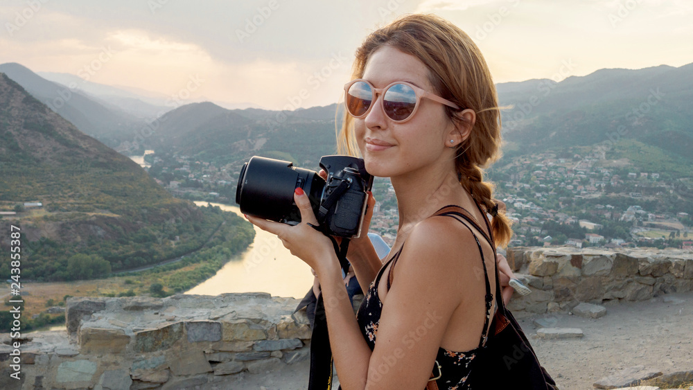 Female photographer, taking pictures of mountain landscape at sunset