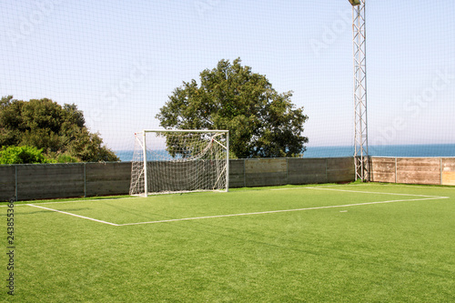 Soccer goal door with white net. Football goal at soccer field with green grass and sport stadium on campus, bleachers, white line and soccer field corner. Sports elements, equipment and environment.