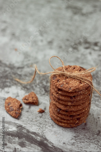 Chocolate chip cookies are stack and tied with twine on stone background