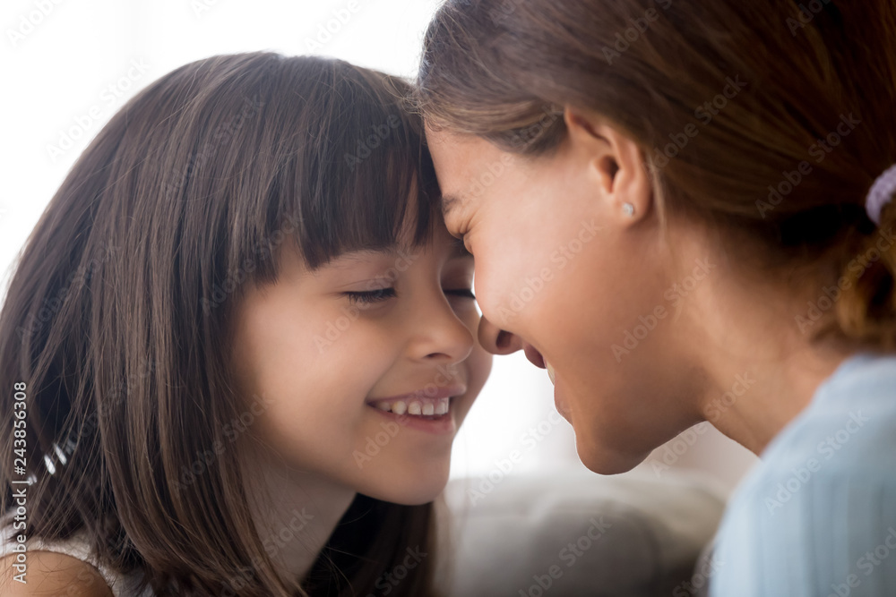 Smiling little child girl enjoying tenderly touching foreheads with happy mom, cute kid daughter and mother having fun bonding feeling love connection enjoy time together, sincere warm relationships Smiling little child girl enjoying tenderly touching foreheads with happy mom, cute kid daughter and mother having fun bonding feeling love connection enjoy time together, sincere warm relationships