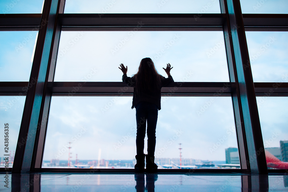 Fototapeta premium Little girl in airport near big window while wait for boarding