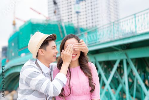 Young man closing his girfriend eyes to make a surprise for her - Love, holiday and people concept photo