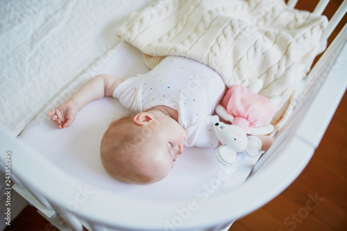 Baby sleeping in co-sleeper crib attached to parents' bed photo