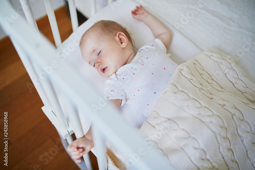 Baby sleeping in co-sleeper crib attached to parents' bed