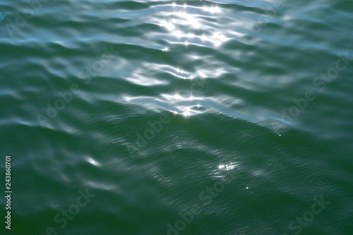 Green water texture with bright patch of light © studiographicmh