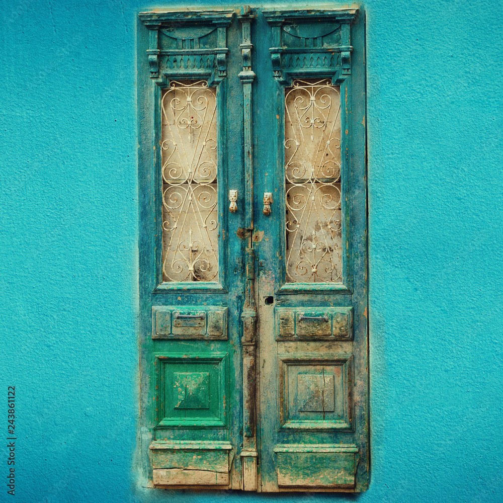 Old turquoise wooden door on blue wall with copy space. Texture background. Pop art concept, vintage style. Square crop Old turquoise wooden door on blue wall with copy space. Texture background. Pop art concept, vintage style. Square crop