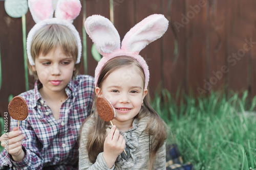 Little girl and boy eat a gingerbread cookie in the shape of the Easter egg.