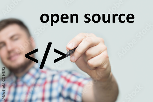 startup programmer writes open source on a glass board with a black marker