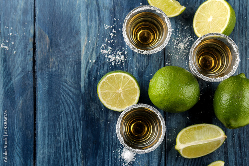 gold tequila in glass glass with salt and lime on a blue wooden background. bar. alcoholic beverages. view from above. with space for text