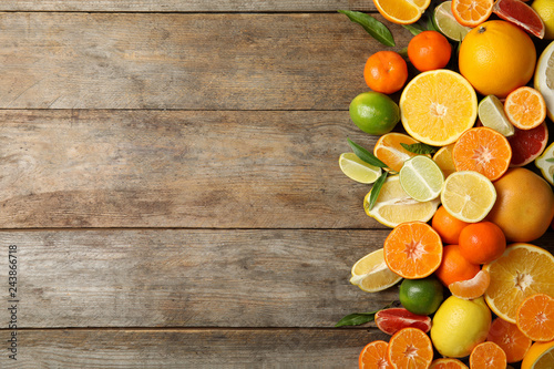 Different citrus fruits on wooden background, top view. Space for text